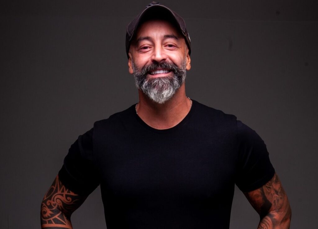Humorista Cris Pereira posa para foto em estúdio com camiseta preta e jeans