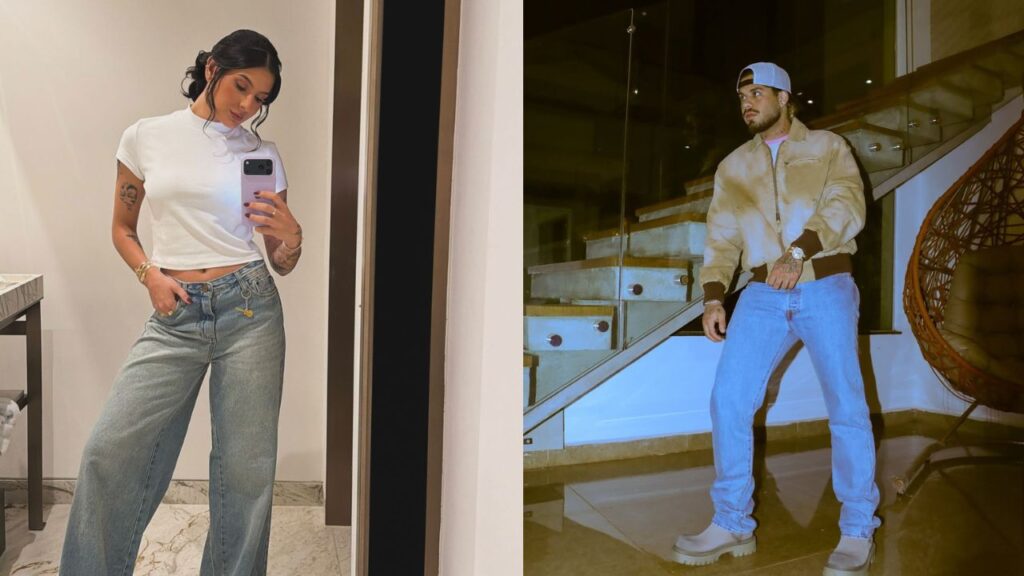 Ana Castela, cantora sertaneja branca de cabelos preto, tira foto no espelho e Zé Felipe, homem branco, vestido com calça jeans e blusa marrom.