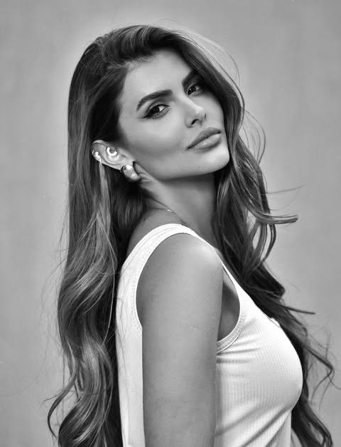 Isabella Arantes posa de perfil com cabelo solto e blusa branca em ensaio fotográfico.