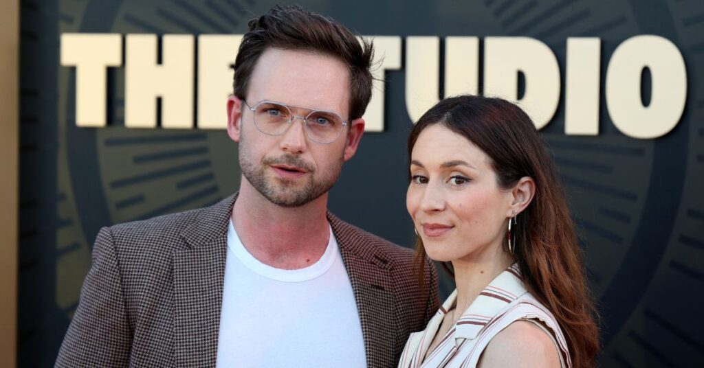Troian Bellisario, de Pretty Little Liars, anuncia 3ª gestação com Patrick Adams Troian Bellisario e Patrick J. Adams, casal de pele clara, posam lado a lado em evento público diante de um painel com o nome “The Studio”. Ele usa terno xadrez marrom e camiseta branca, enquanto ela veste roupa clara listrada, ambos com expressões serenas e elegantes sob luz natural.