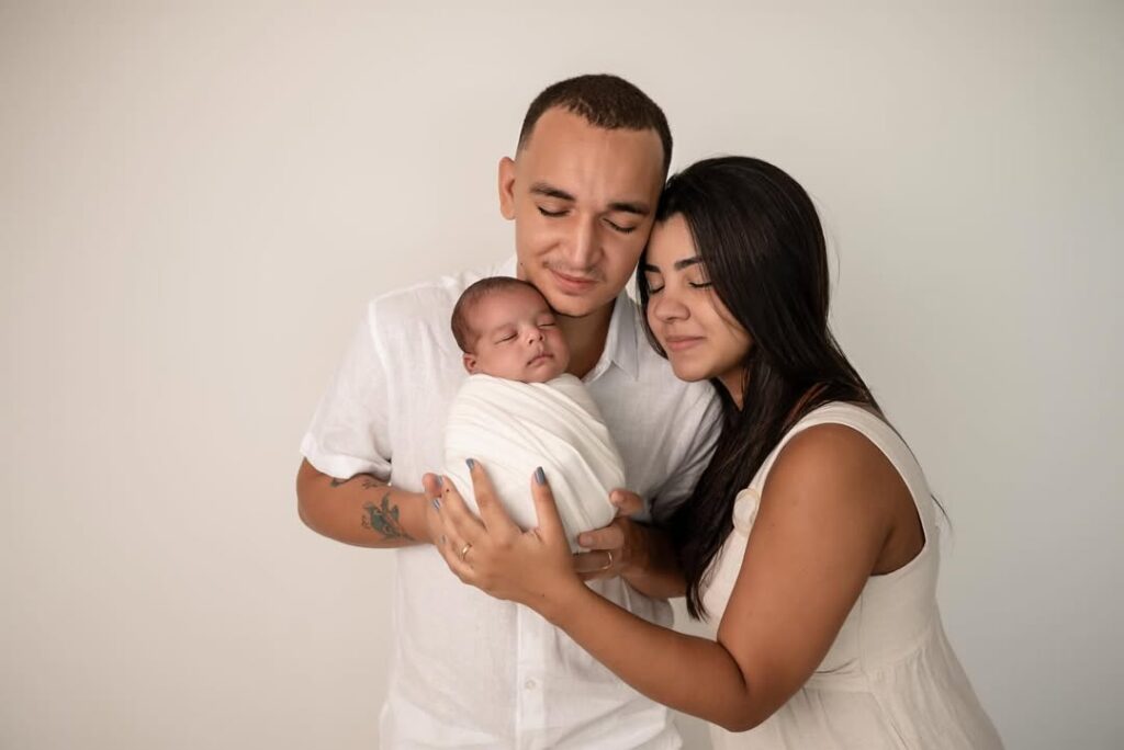 Chegadas que emocionaram: relembre os bebês de famosos que nasceram em 2025 5 João Gomes e mulher seguram o bebê recém-nascido em estúdio, em retrato com fundo neutro.