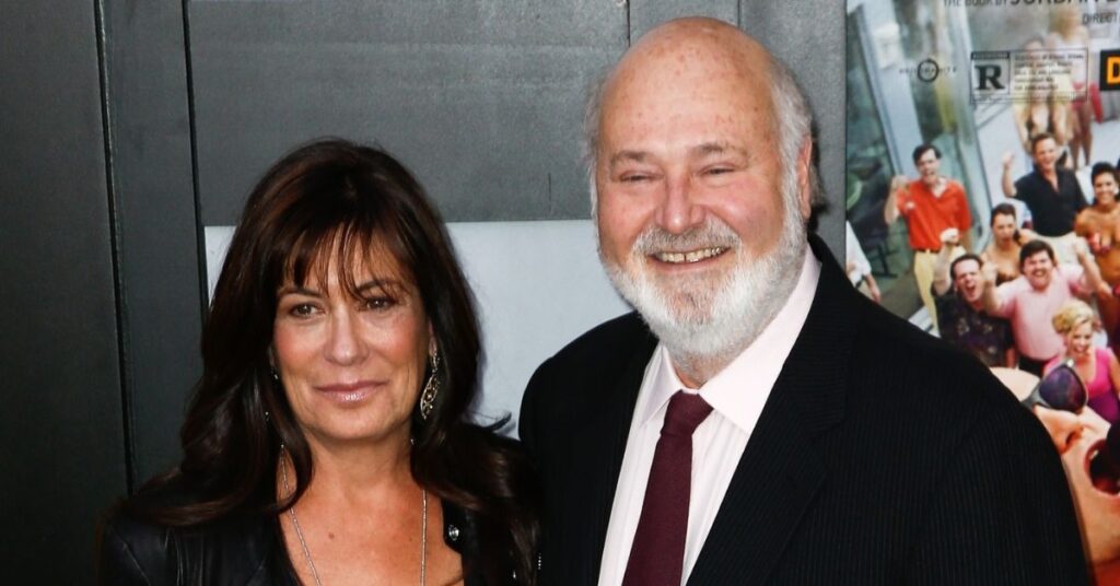 Rob Reiner e Michele Singer posam juntos em evento público, sorrindo para a câmera, diante de painel com pôsteres de filmes ao fundo.