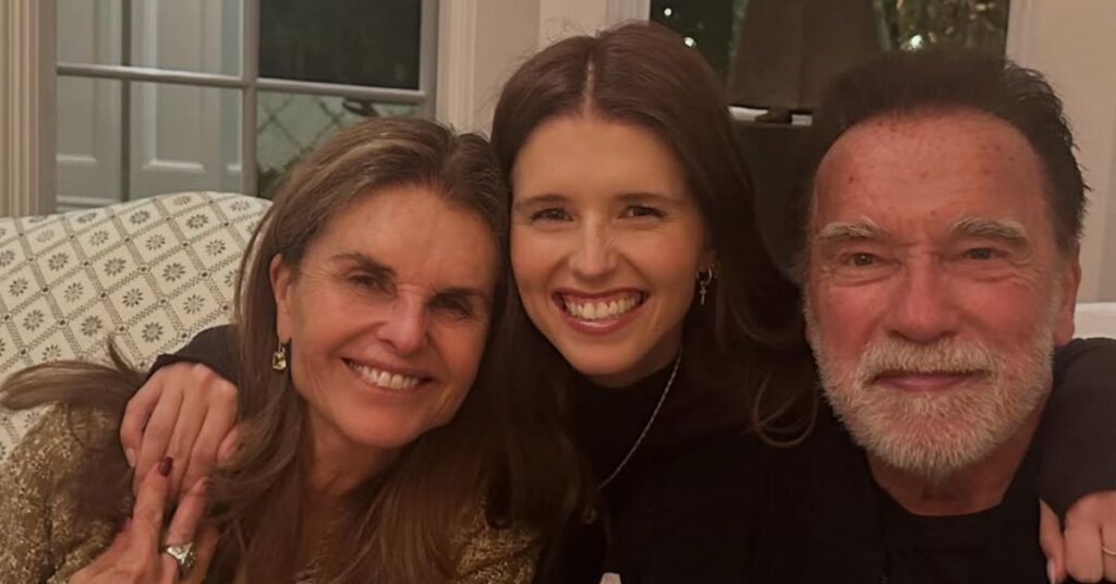 Arnold Schwarzenegger posa sorridente ao lado da ex-esposa Maria Shriver e da filha Katherine durante reunião de Natal em família, em ambiente interno e clima descontraído