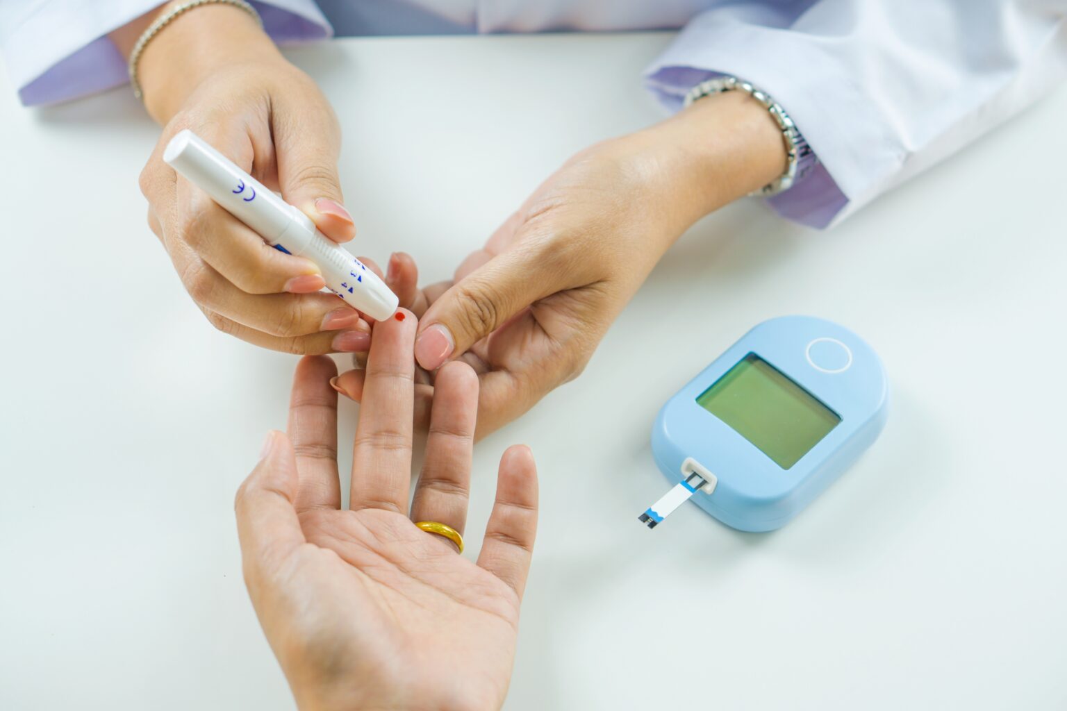 Profissional de saúde mede a glicose no sangue com teste no dedo, ilustrando o monitoramento do pré-diabetes e do controle glicêmico.