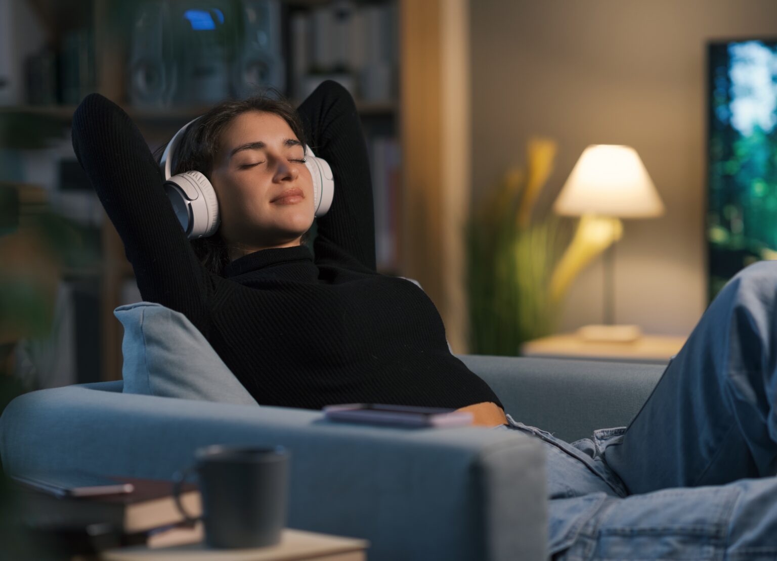 3 regras seguidas por pessoas mais felizes ajudam a reduzir a ansiedade no dia a dia Mulher relaxando no sofá com fones de ouvido, representando bem-estar emocional, redução da ansiedade e busca por equilíbrio no dia a dia