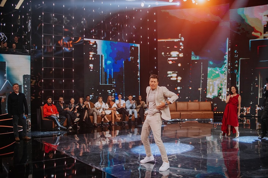 Rodrigo Faro durante apresentação no palco do programa Dança dos Famosos, em cena artística iluminada.