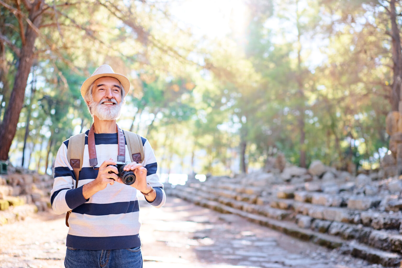Quer viajar depois dos 60? Estes 10 destinos unem conforto, lazer e segurança Homem com mais de 60 anos viajando e fotografando paisagem, exemplo de turismo com conforto, lazer e segurança na terceira idade