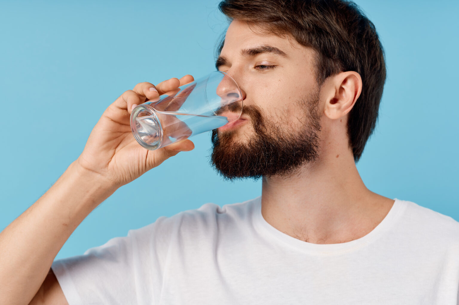 Regra dos 2 litros cai por terra: estudo revela quanta água o corpo realmente precisa Homem bebendo um copo de água, ilustrando hábitos de hidratação e o debate sobre a quantidade ideal de água que o corpo precisa por dia.