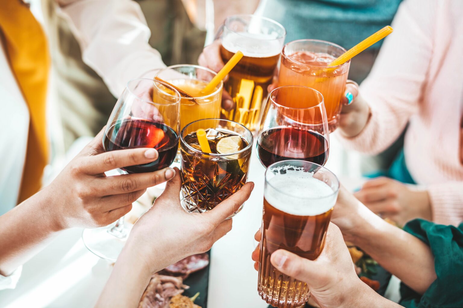 Álcool aumenta o risco de AVC, mesmo em doses moderadas; veja 10 bebidas que merecem atenção Grupo de pessoas brindando com diferentes bebidas alcoólicas, como cerveja, vinho e coquetéis, ilustrando consumo de álcool associado ao aumento do risco de AVC.