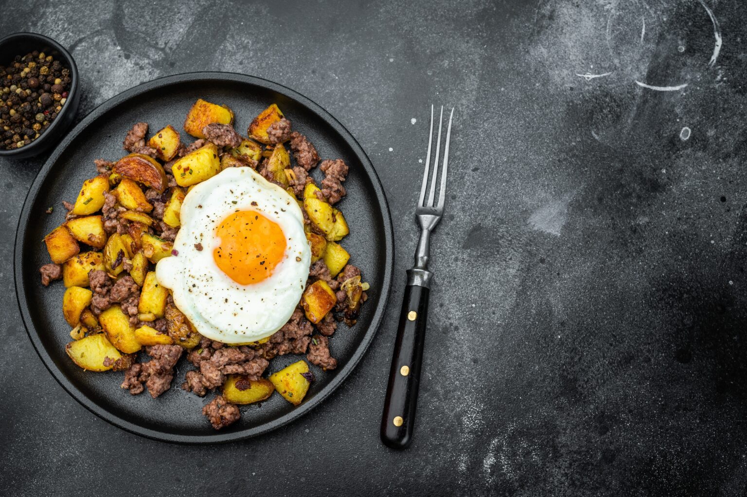 Ovo na dieta: formas criativas de consumir para aumentar a massa muscular Prato com ovo frito, carne e batatas douradas, exemplo de refeição rica em proteínas para aumentar a massa muscular