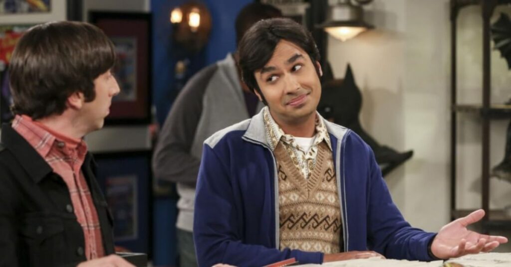 Kunal Nayyar como Raj em cena de The Big Bang Theory conversando com Howard na cozinha do apartamento