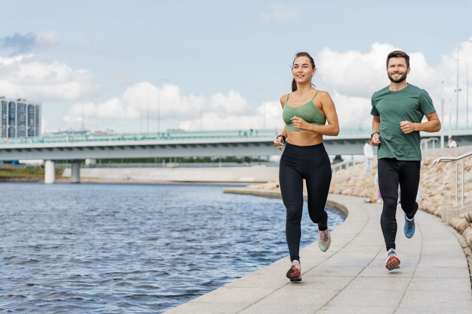Você está fazendo cardio demais? Descubra a frequência ideal para perder gordura Homem e mulher praticando cardio ao ar livre, correndo à beira de um lago em treino aeróbico para perder gordura.