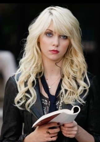 Taylor Momsen com cabelos loiros longos, segurando um livro e usando jaqueta preta, imagem que relembra uma das celebridades que sumiram da televisão após o sucesso em séries teen dos anos 2000.