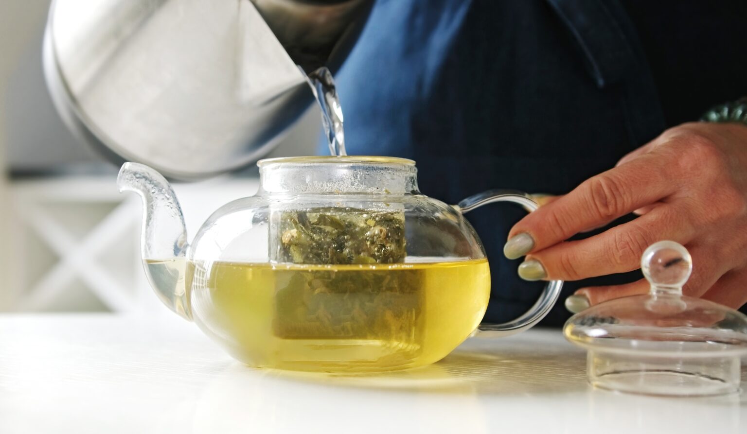 Chá verde sendo preparado com água quente em bule de vidro para preservar seus benefícios naturais