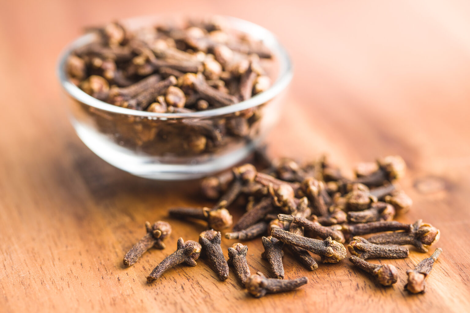 Cravo-da-índia em recipiente de vidro sobre mesa de madeira, especiaria usada para ferver cravo e afastar mosquitos naturalmente.