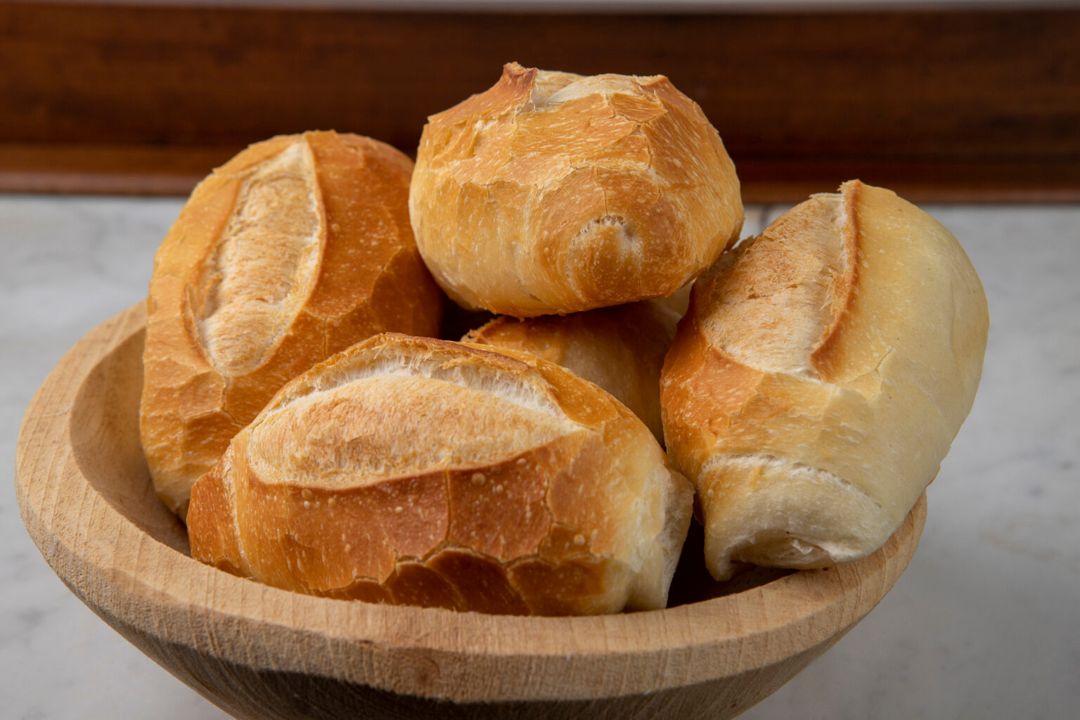 Pães franceses em tigela de madeira, com casca dourada e crocante, ideais para explicar como conservar pão francês por dias sem perder crocância