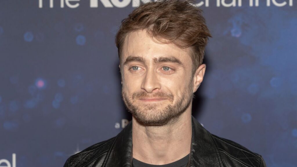 Daniel Radcliffe posa em evento usando jaqueta preta e aparece sério durante entrevista sobre fase difícil após Harry Potter.