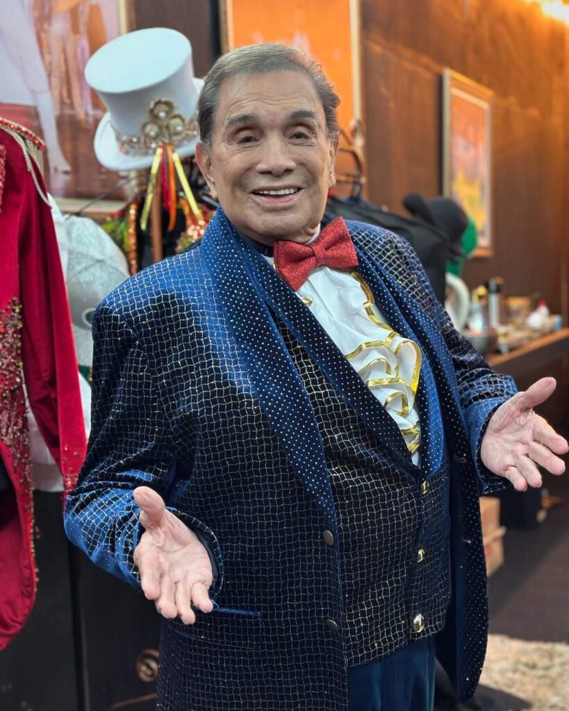 Famosos que perderam tudo: 10 celebridades que enfrentaram crises financeiras e deram a volta por cima 6 Dedé Santana sorridente com traje elegante nos bastidores representando famosos que perderam tudo