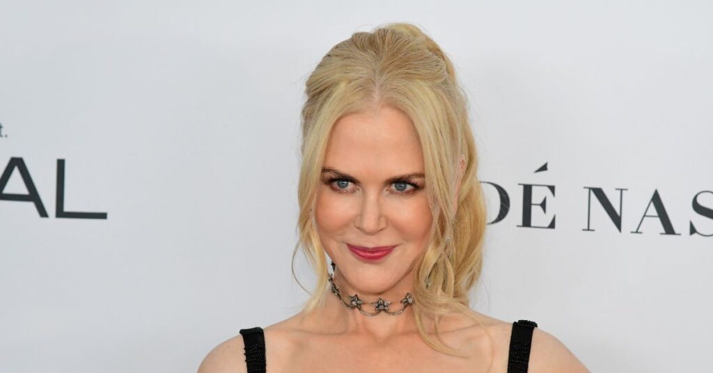 Nicole Kidman e Simon Baker juntos teriam causado ciúmes em Keith Urban; entenda Nicole Kidman, mulher loira com cabelo preso e maquiagem leve, posa sorrindo em evento, usando vestido preto e colar delicado.