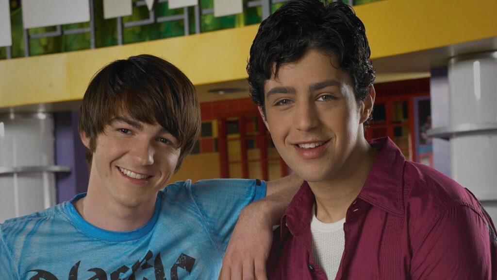 Drake Parker e Josh Nichols, protagonistas da série Drake & Josh, aparecem sorrindo lado a lado em cena ambientada dentro da escola.