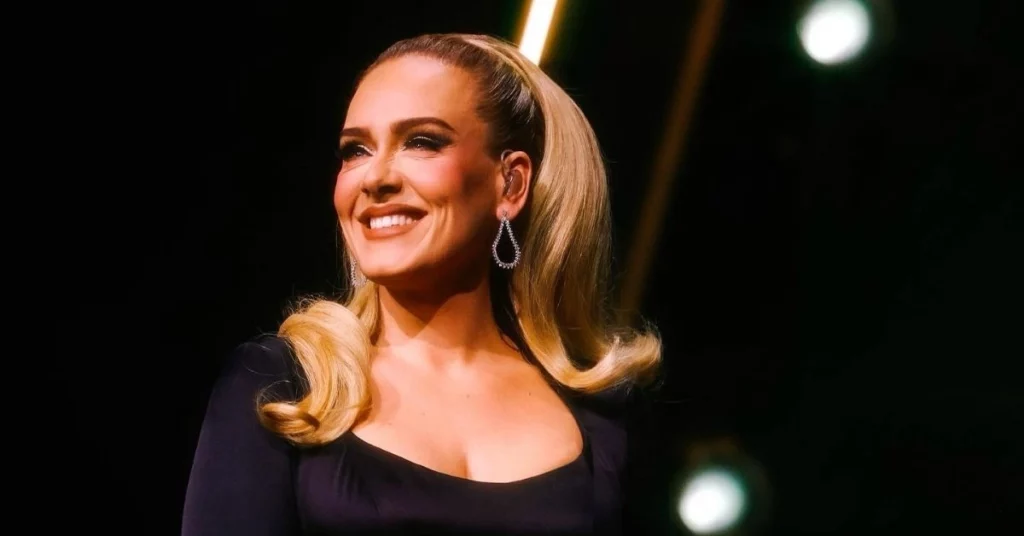 Adele muda os rumos da carreira e decisão acende alerta entre amigos; entenda Adele sorrindo durante apresentação com iluminação de palco, em momento de transição da carreira para o cinema