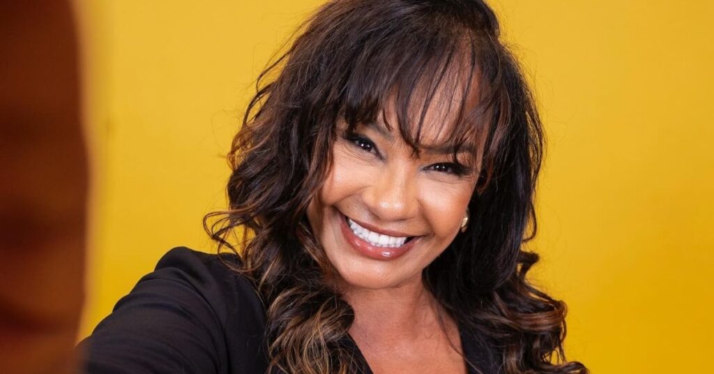 Solange Couto sorri em retrato oficial com fundo amarelo após participação no BBB 26