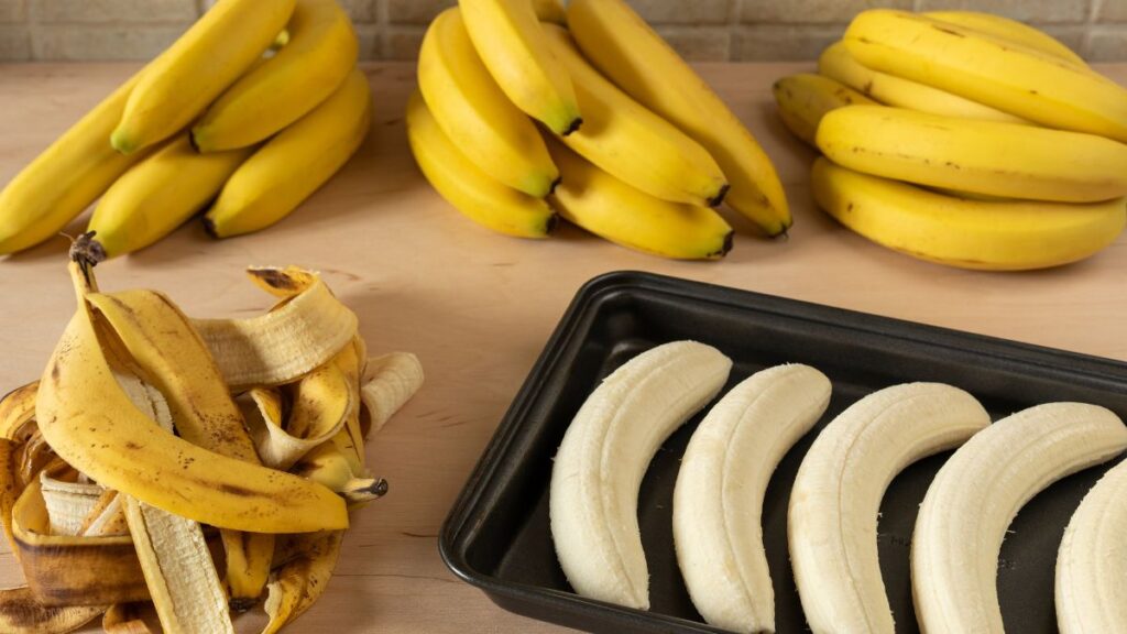 Cascas de banana ao lado de bananas descascadas organizadas em bandeja, mostrando aproveitamento da fruta e uso da casca de banana na pele como alternativa natural
