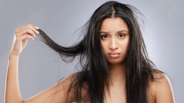 mulher com cabelo com frizz visível segurando mecha ressecada, ilustrando fios desalinhados e necessidade de tratamento capilar hidratante