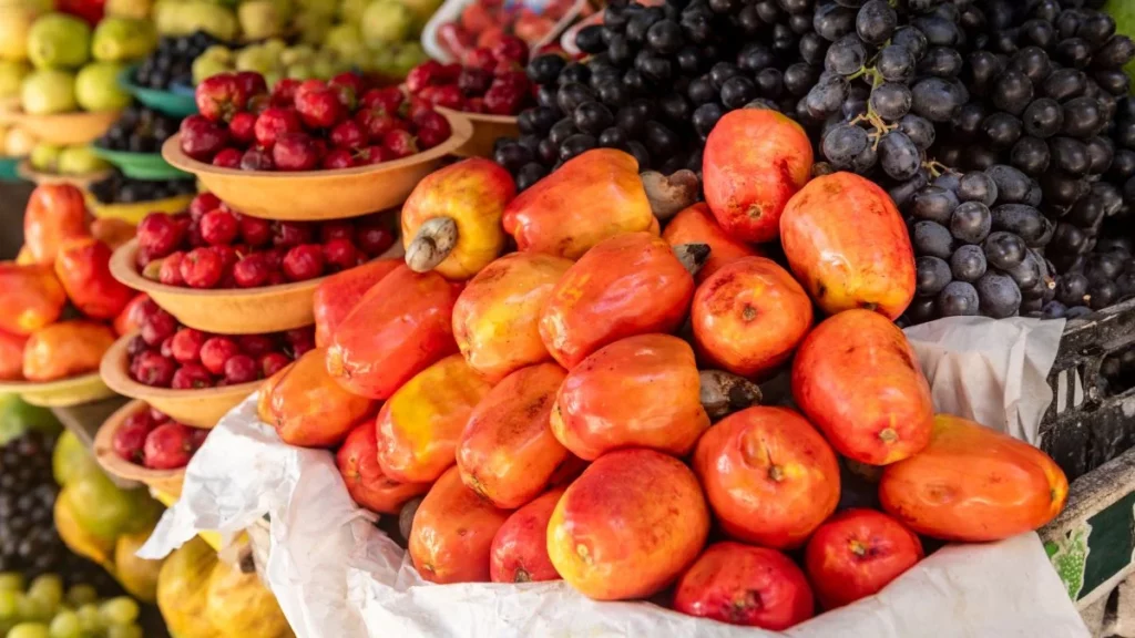 variedade de frutas frescas em feira com caju, uvas e frutas tropicais expostas em bancas representando diversidade de frutas brasileiras no ranking global