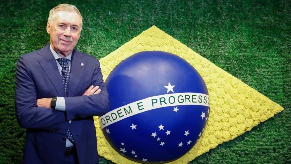 Carlo Ancelotti posa de braços cruzados diante de um painel com elementos da bandeira do Brasil durante evento oficial da Seleção Brasileira.
