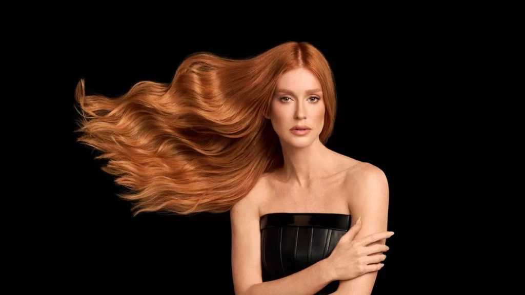Marina Ruy Barbosa com cabelo ruivo esvoaçante em fundo preto, representando a evolução visual da atriz no conteúdo sobre marina ruy barbosa antes e depois.