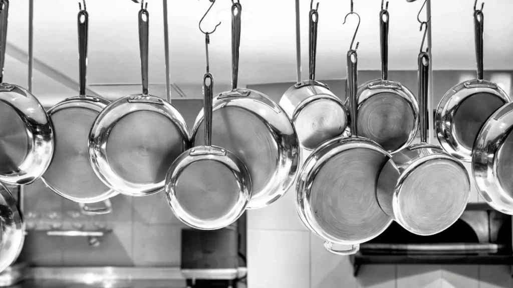 Panela de inox manchada? Esse truque simples resolve sem esforço Como limpar panela de inox: conjunto de panelas penduradas com superfície brilhante e sem manchas