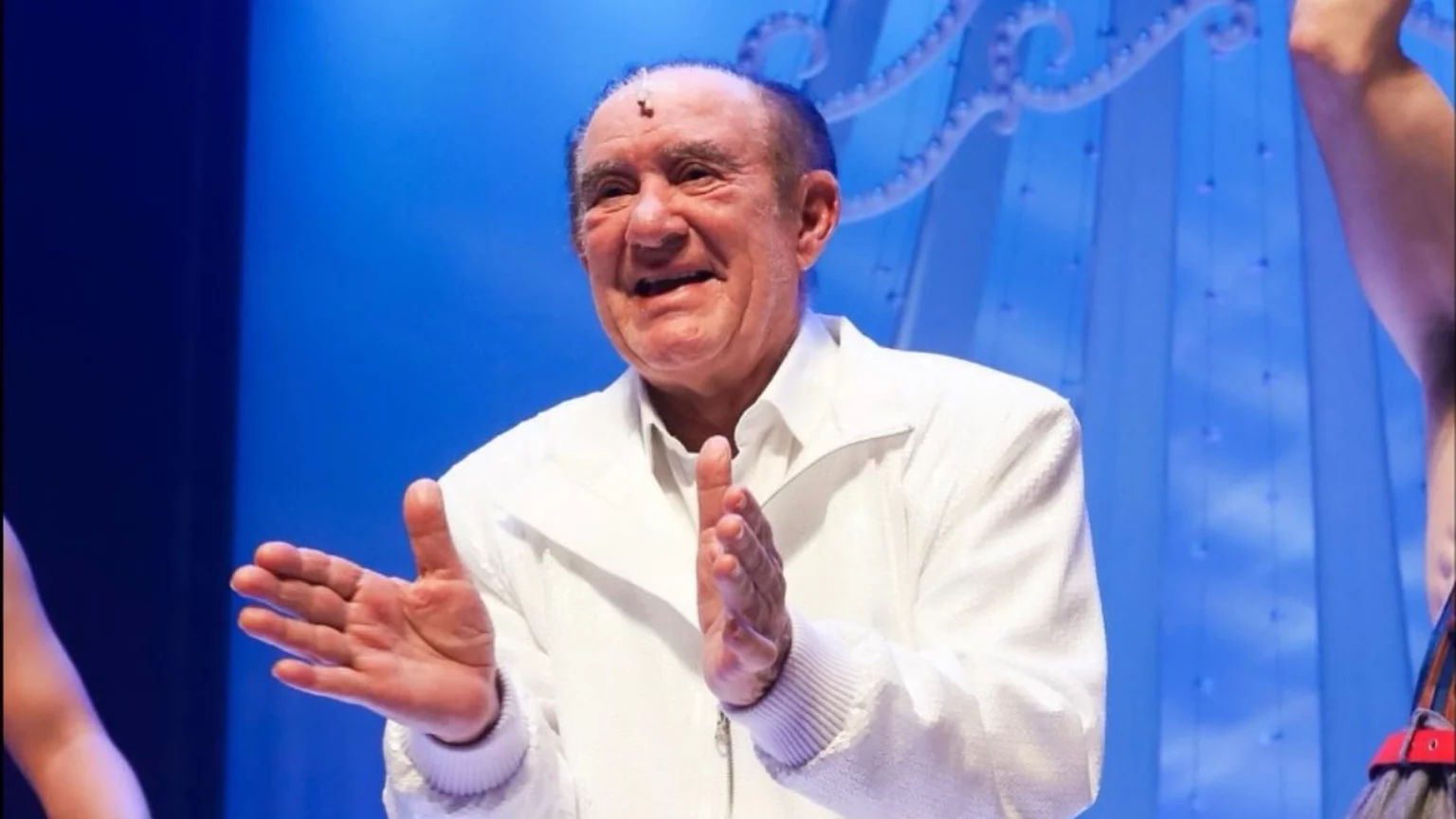 Prefeitura do Rio tenta bloquear mansão de Renato Aragão após dívida de IPTU; entenda Renato Aragão aparece sorrindo e aplaudindo durante apresentação em palco iluminado por luzes azuis