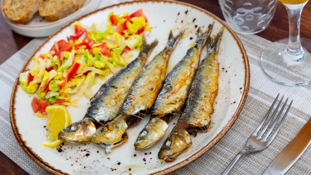 prato com sardinhas grelhadas servidas com salada e limão