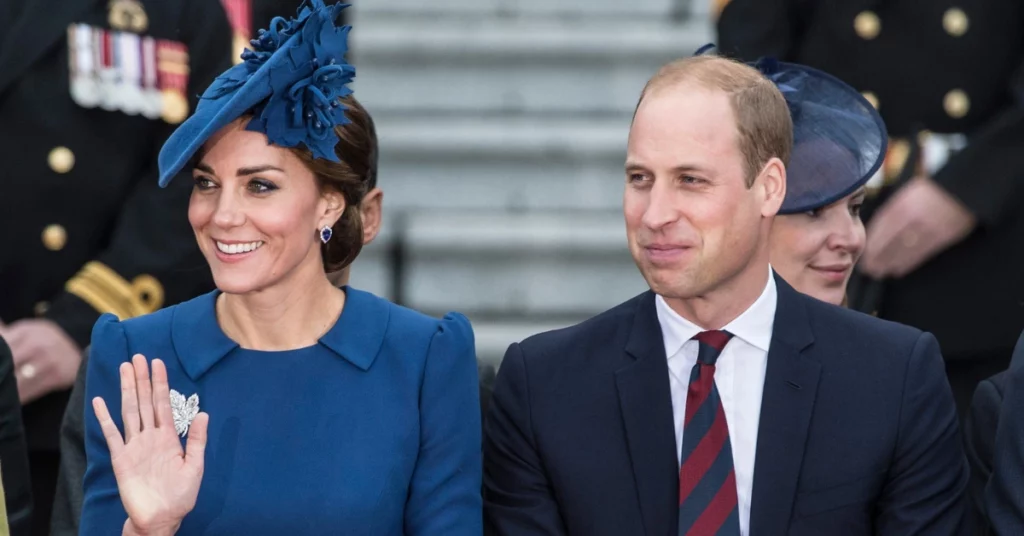Kate Middleton acena ao lado do príncipe William durante evento da família real britânica, ambos usando trajes em tons de azul