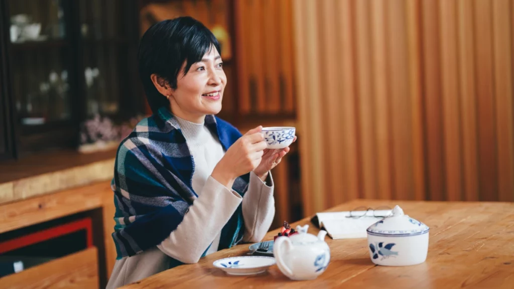 Mulher na menopausa tomando chá em ambiente aconchegante, ilustrando hábitos associados ao bem-estar e ao equilíbrio metabólico