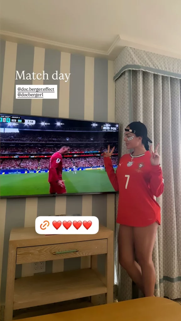 Georgina Rodríguez posa ao lado da TV usando camisa de Portugal enquanto Cristiano Ronaldo aparece em jogo da Copa