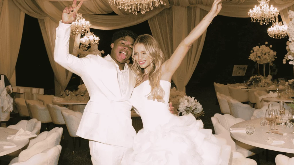 Namorada do Endrick: idade, Instagram e curiosidades sobre Gabriely Miranda Imagem sobre Namorada do Endrick mostra casal em festa de casamento, vestido de branco, sorrindo em salão decorado com lustres.