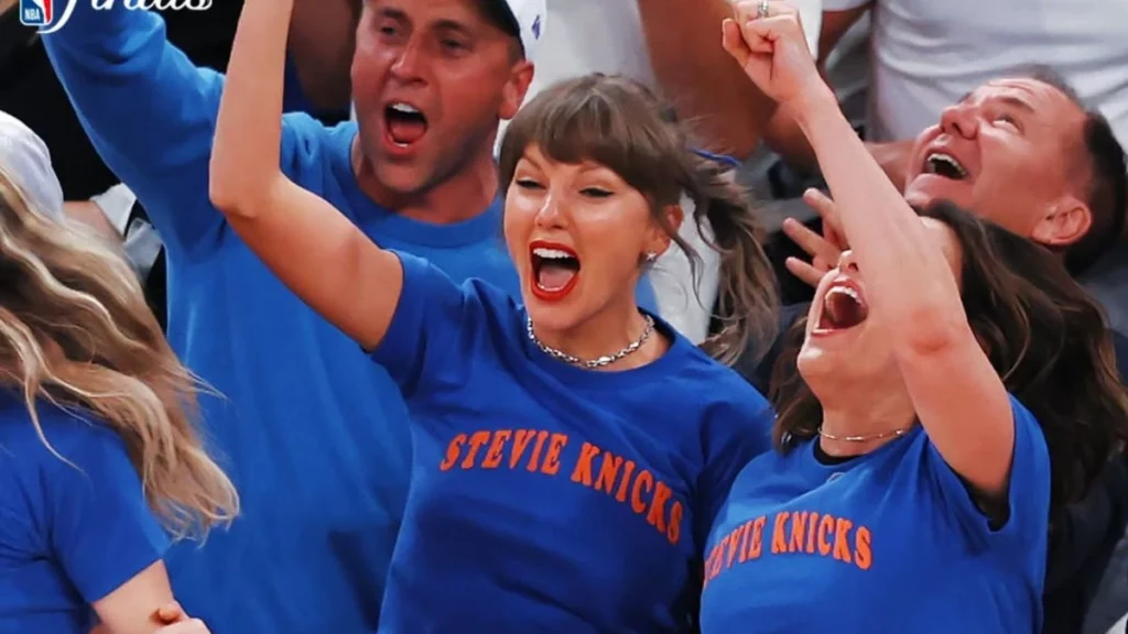 Cadeira de Taylor Swift na NBA é leiloada por R$ 38 mil; entenda Taylor Swift comemora e reage com entusiasmo durante partida de basquete, usando camiseta azul nas arquibancadas e interagindo com amigos e torcedores.