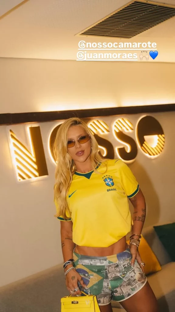 Virginia Fonseca posa com camisa amarela da Seleção Brasileira e bolsa amarela em camarote no Maracanã.