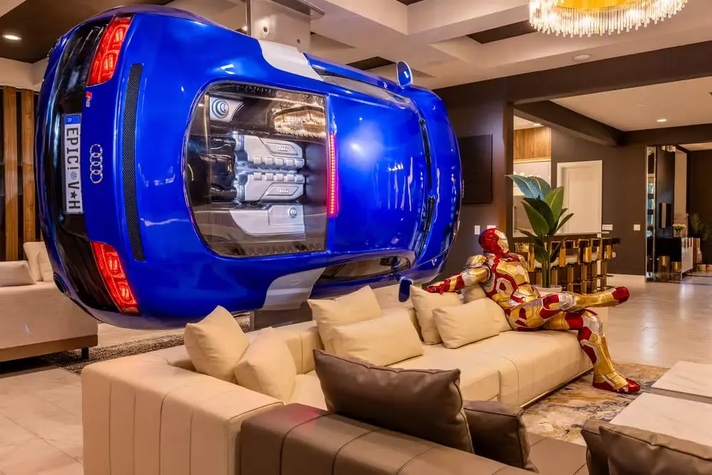 Virginia se hospeda em mansão de luxo em Orlando e valor impressiona; veja 1 Sala da mansão com sofá claro, escultura inspirada no Homem de Ferro e carro esportivo azul em tamanho real integrado à decoração.