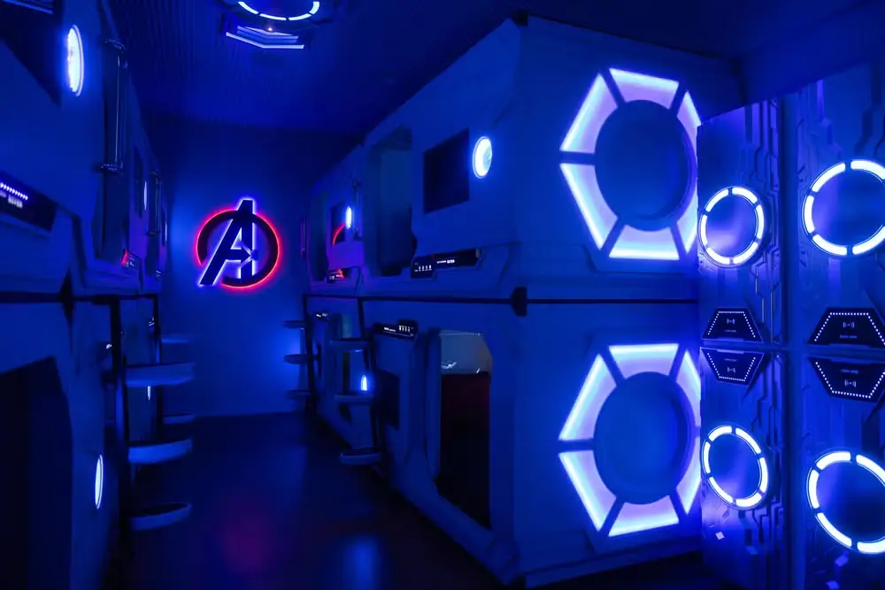 Virginia se hospeda em mansão de luxo em Orlando e valor impressiona; veja 5 Quarto temático com iluminação azul neon, camas em formato de cápsulas futuristas e símbolo dos Vingadores iluminado na parede.