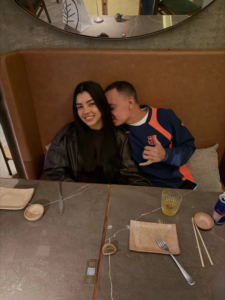 Ary Mirelle e João Gomes sorriem abraçados durante encontro romântico em restaurante.