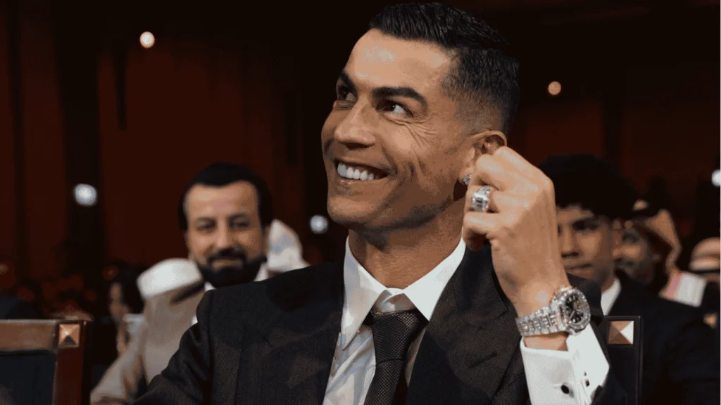 Fortuna de Cristiano Ronaldo: quanto ele tem em 2026? Fortuna de Cristiano Ronaldo é tema de imagem de capa com jogador sorrindo em evento formal.