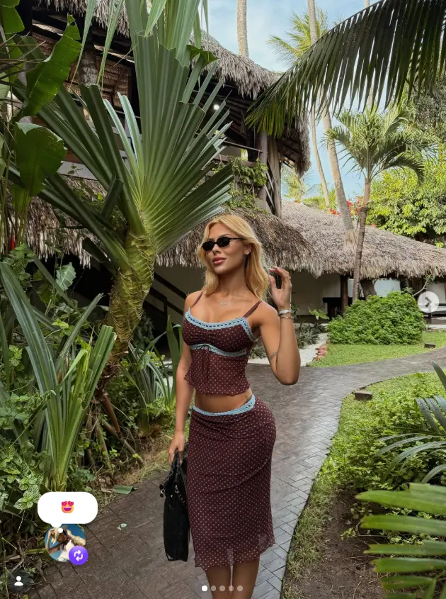 Print de uma republicação (repost) no Instagram, mostrando a foto original da influenciadora posando em um ambiente tropical luxuoso. Sobreposta no canto inferior esquerdo está a reação do republicador (o cantor, conforme o texto), com um emoji de rosto apaixonado (olhos de coração) e o ícone de repost.