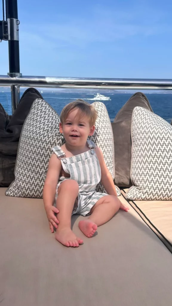 Uma criança posa sorrindo em área de descanso de um barco durante passeio na Itália.