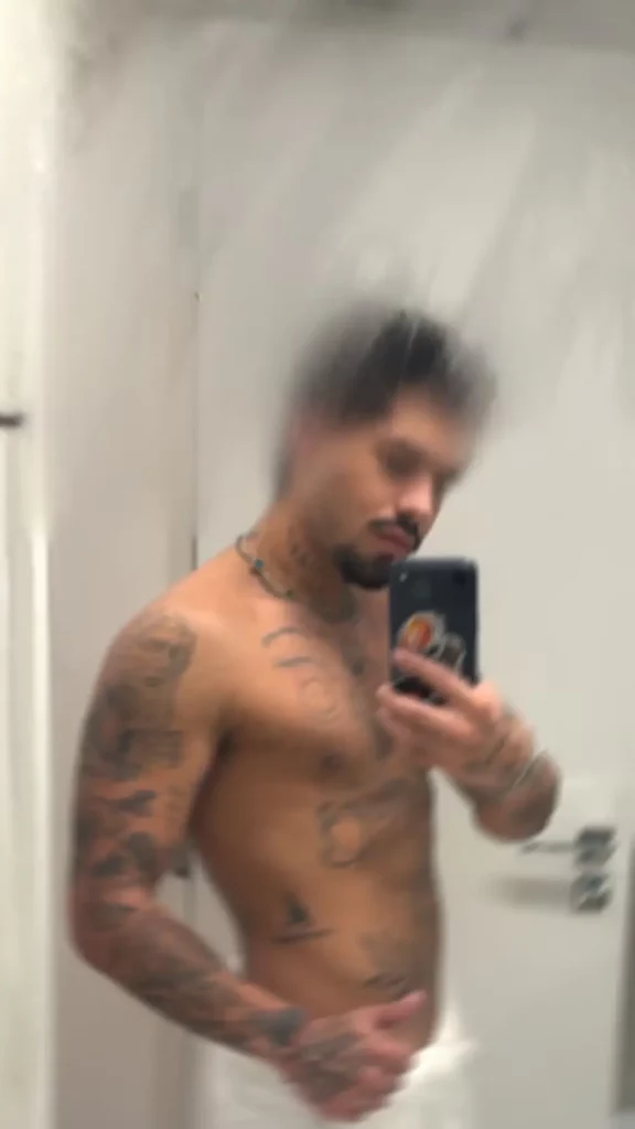 Zé Felipe revela real motivo de fase reclusa: 'preciso disso' 6 Selfie tremida e levemente desfocada do cantor Zé Felipe em frente ao espelho. Ele está sem camisa, usando uma toalha branca na cintura e exibindo várias tatuagens nos braços e no peito enquanto segura o celular.