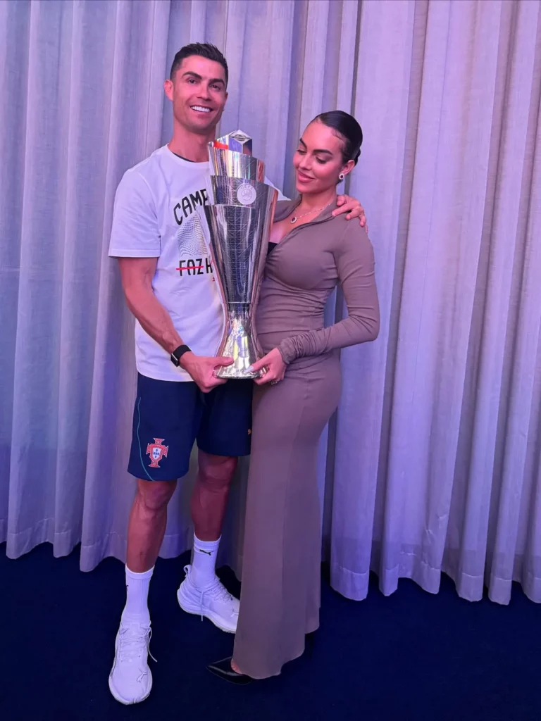 Cristiano Ronaldo e Georgina Rodríguez posando de pé com um grande troféu de prata.