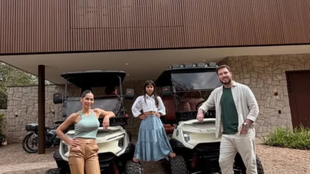 Maíra Cardi, Thiago Nigro e uma criança posam em frente à nova mansão da família, ao lado de carrinhos de golfe
