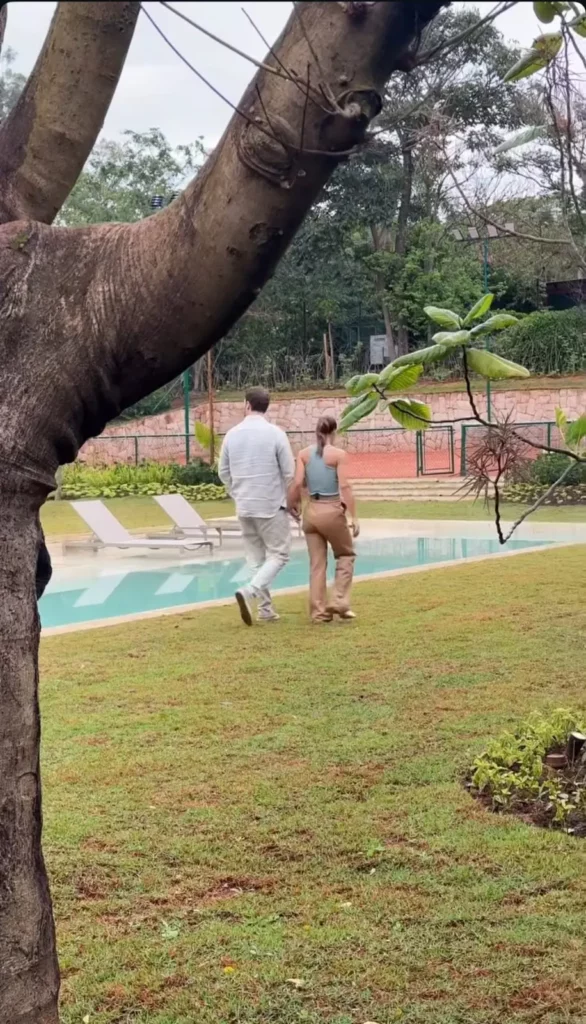 Maíra Cardi e Thiago Nigro caminham pela área externa da nova mansão ao lado da piscina